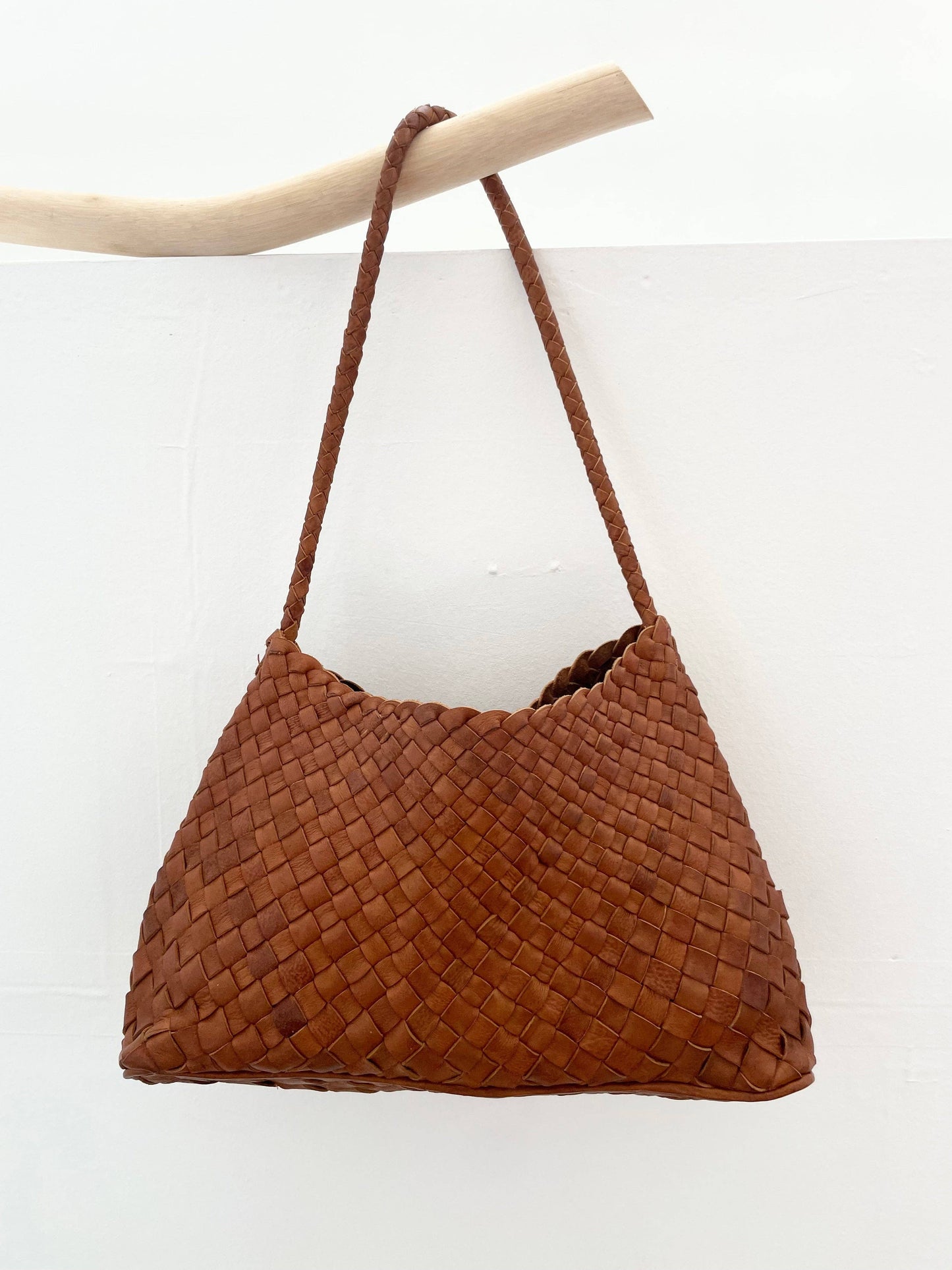 Palar Tan Bag hanging from a branch against a white background