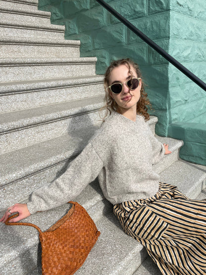 Model seated on steps beside the Palar Tan Bag in a relaxed street-style look
