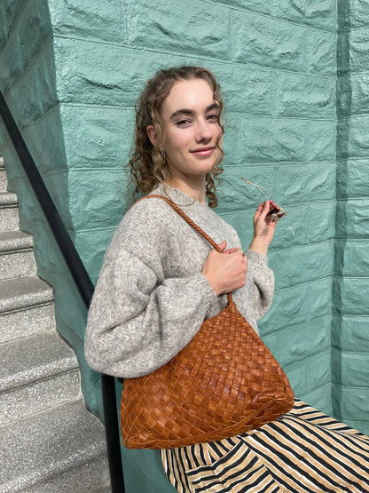 Seated model carrying the Palar Tan Bag against a mint green wall