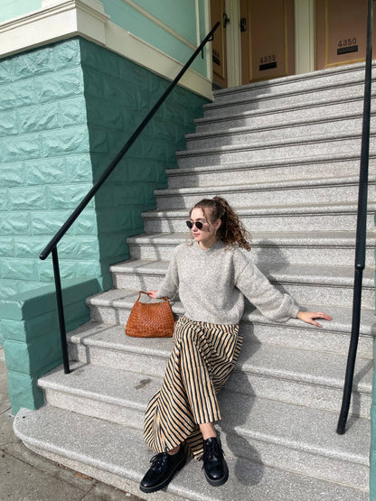 Model seated on outdoor steps with the Palar Tan Bag beside her