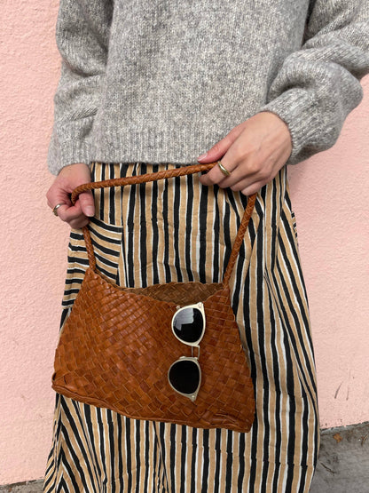 Palar Tan Bag worn at the hip with sunglasses tucked into the woven leather exterior