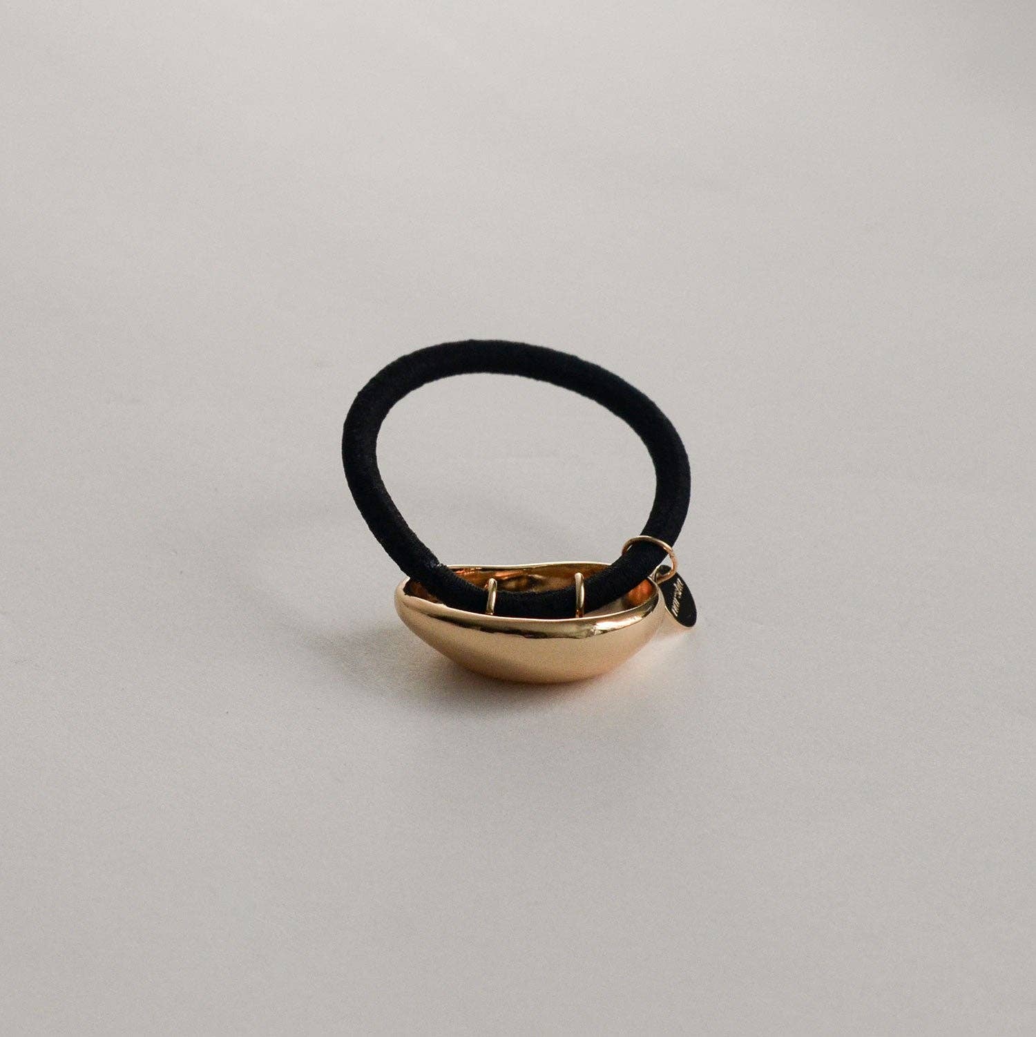 Back view of the gold metal cuff hair tie showing the black elastic and cuff attachment.