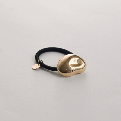 Side view of the sculptural gold pebble cuff hair tie with a smooth polished finish.