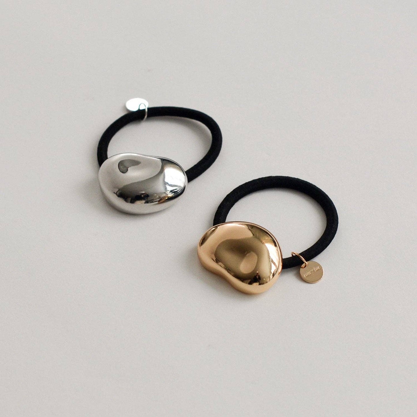 Gold and silver pebble-shaped metal cuff hair ties displayed together on a light background.