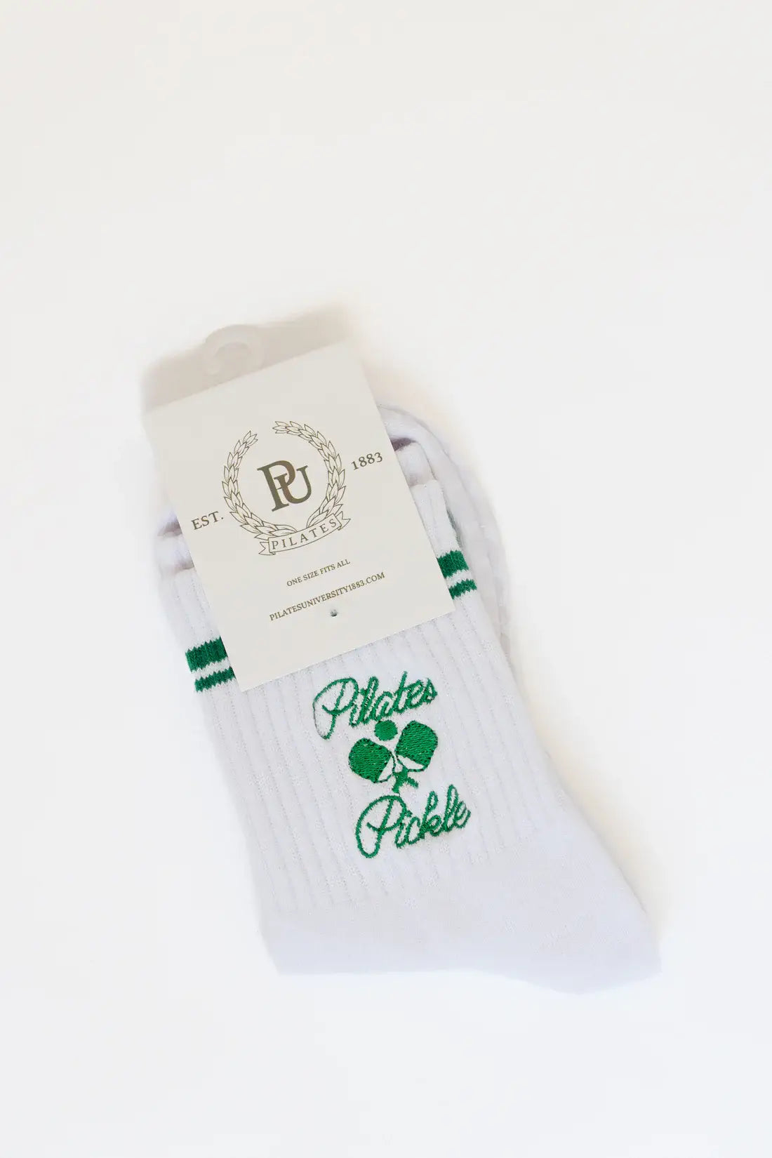 Folded pair of white Pilates Pickle crew socks with green embroidered pickleball graphic and varsity stripes, displayed with branded packaging card.
