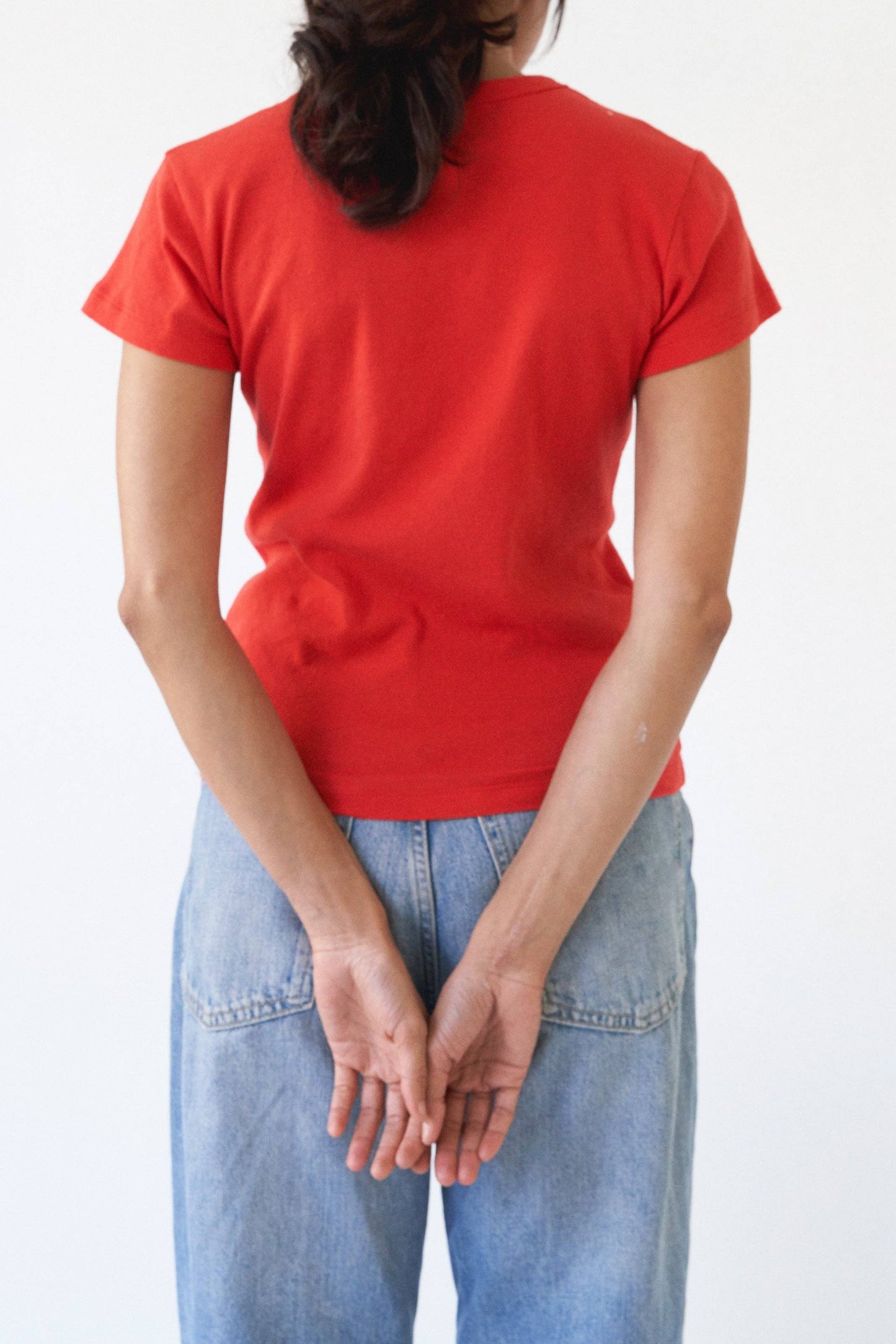 Back view of the Pointelle Baby Tee in red orange styled with light wash jeans.