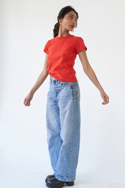 Model wearing the Pointelle Baby Tee in red orange with relaxed light wash jeans for an easy everyday look.