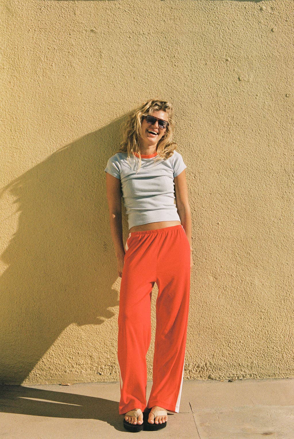 Full-length front view of the coral red Pointelle Track Pant with an elasticated waist and straight legs.