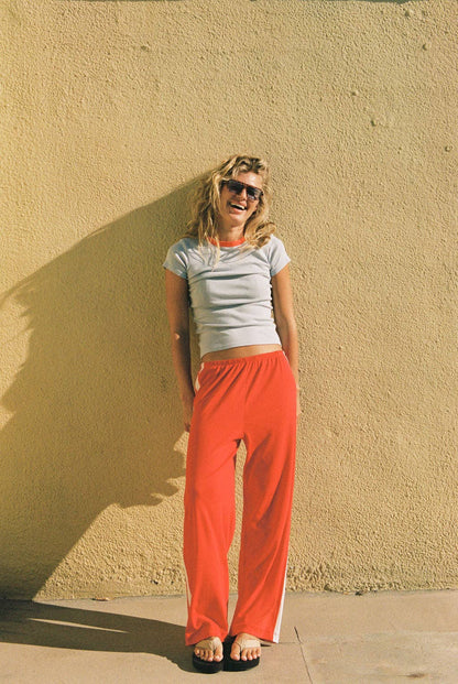 Full-length front view of the coral red Pointelle Track Pant with an elasticated waist and straight legs.