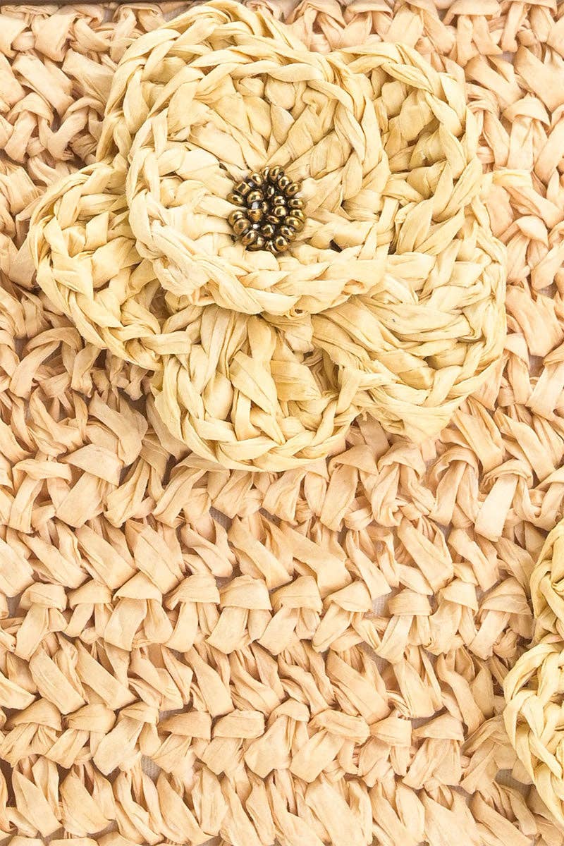 Close-up of the woven beige raffia texture and floral raffia embellishment on the Raffia Top-Handle Tote.