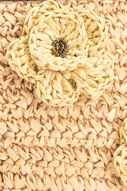 Close-up of the woven beige raffia texture and floral raffia embellishment on the Raffia Top-Handle Tote.