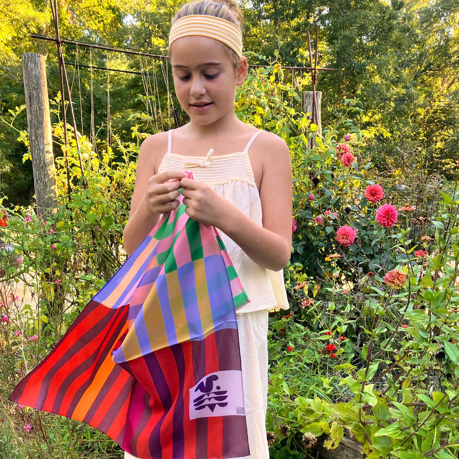 Model styling the Red Colorblock silk scarf outdoors, showing its lightweight drape and colorful silk finish.