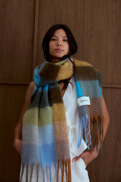 Female model wearing the Blue/Orange Reykjavik Scarf in an indoor lifestyle setting