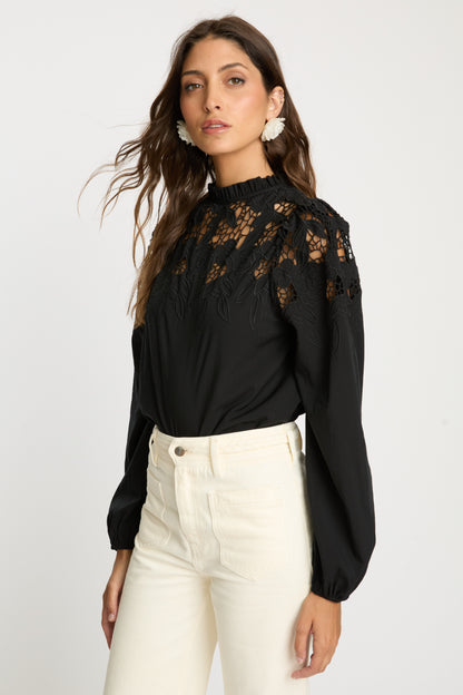 Angled front view of the Riana Reversible Top in black showcasing embroidered floral lace detailing across the shoulders and bodice, sheer panels, and voluminous long sleeves.