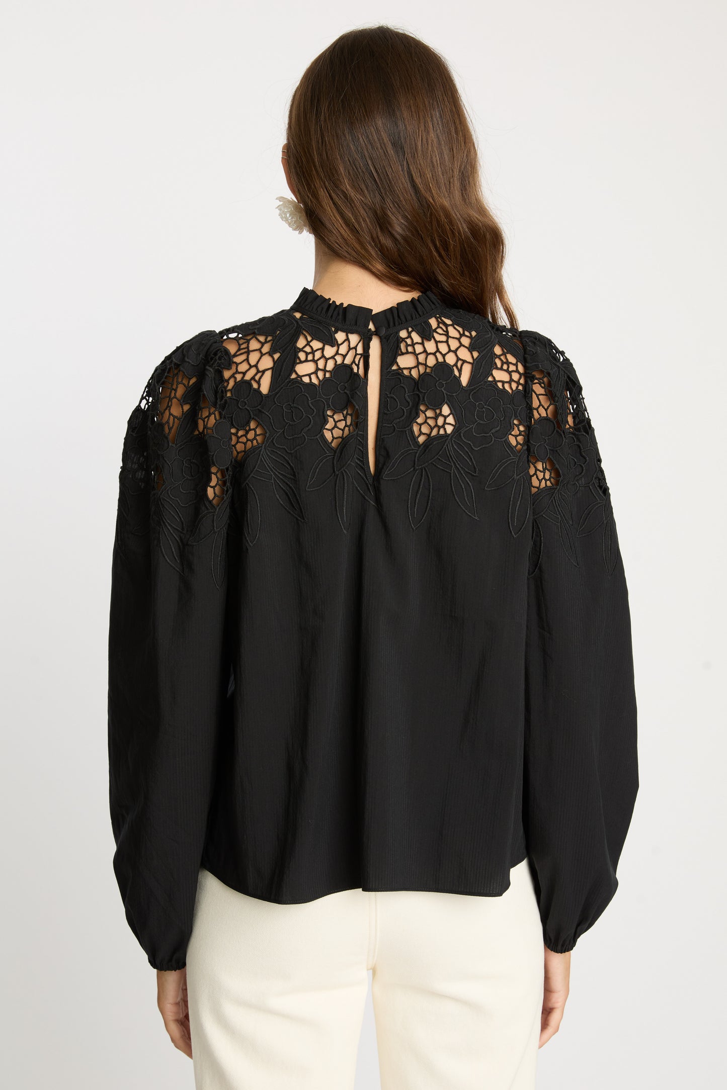 Rear detail view of the Riana Reversible Top in black showcasing semi-sheer floral lace panels, embroidered shoulder detailing, keyhole back closure, and long sleeves with gathered cuffs.