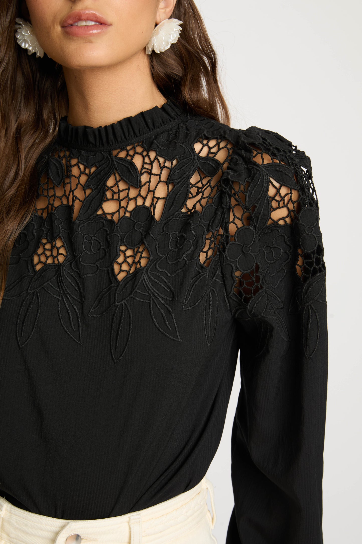 Close-up detail of the Riana Reversible Top in black highlighting the intricate floral lace embroidery, semi-sheer mesh panels, and high ruffled neckline.