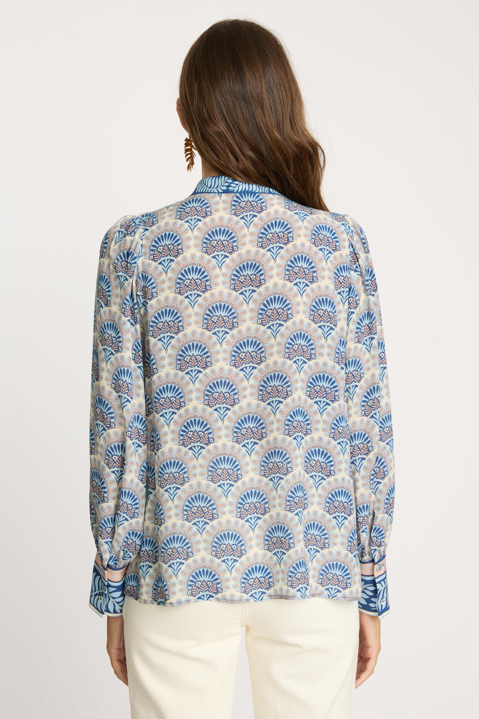 Model wearing the Riley Top in Boho Deco from the back, featuring an intricate blue and beige bohemian-inspired print, relaxed silhouette, and long sleeves with contrasting cuff details.