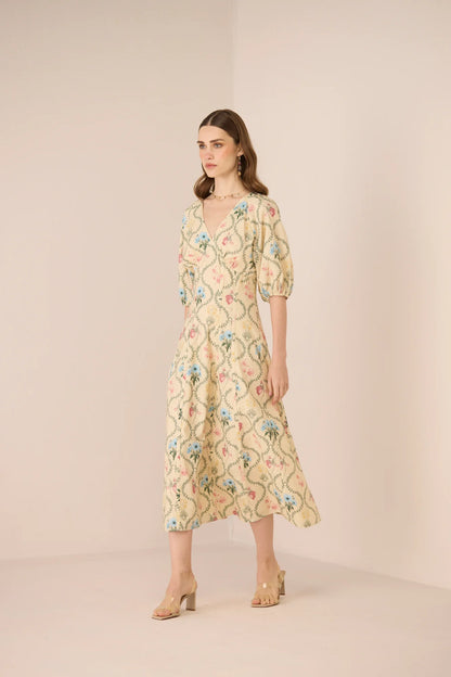 Model wearing the Rosewood Midi Dress from an angled front view, highlighting the fitted waist, soft puff sleeves, and airy midi silhouette.