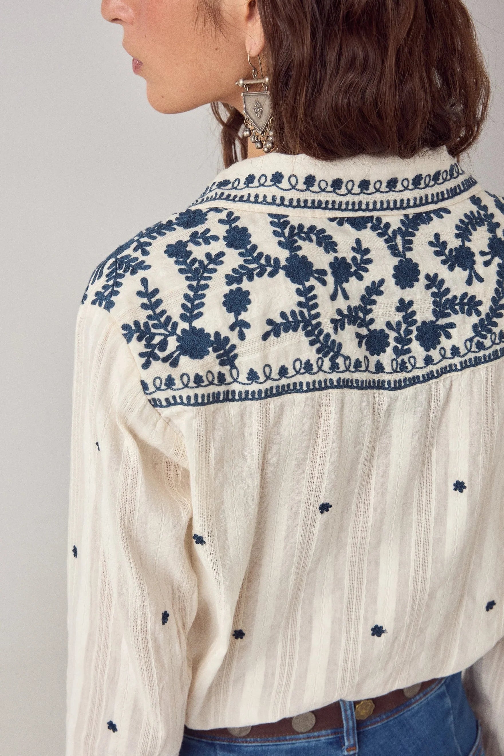 Close-up of the back yoke on the Salinger Shirt in Cream Indigo featuring intricate navy floral embroidery and woven stripe texture.