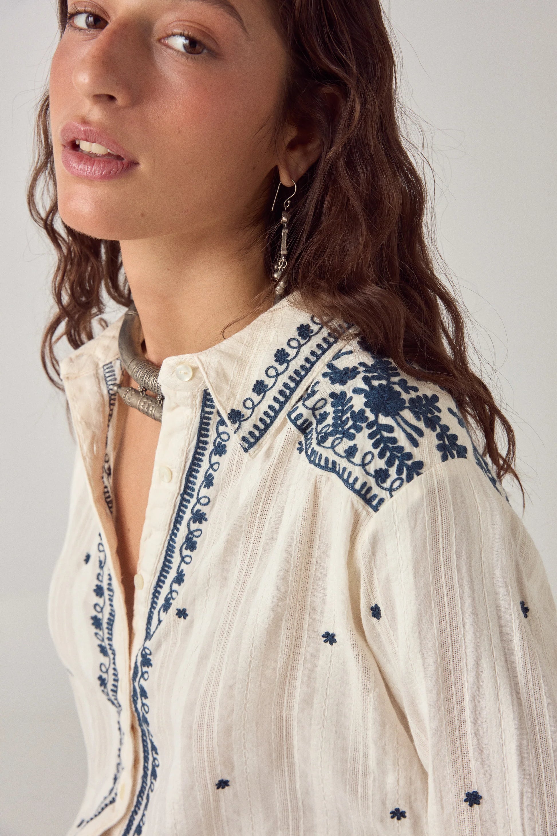 Close-up of the Salinger Shirt in Cream Indigo highlighting intricate navy floral embroidery along the collar, shoulder yoke, and front placket.