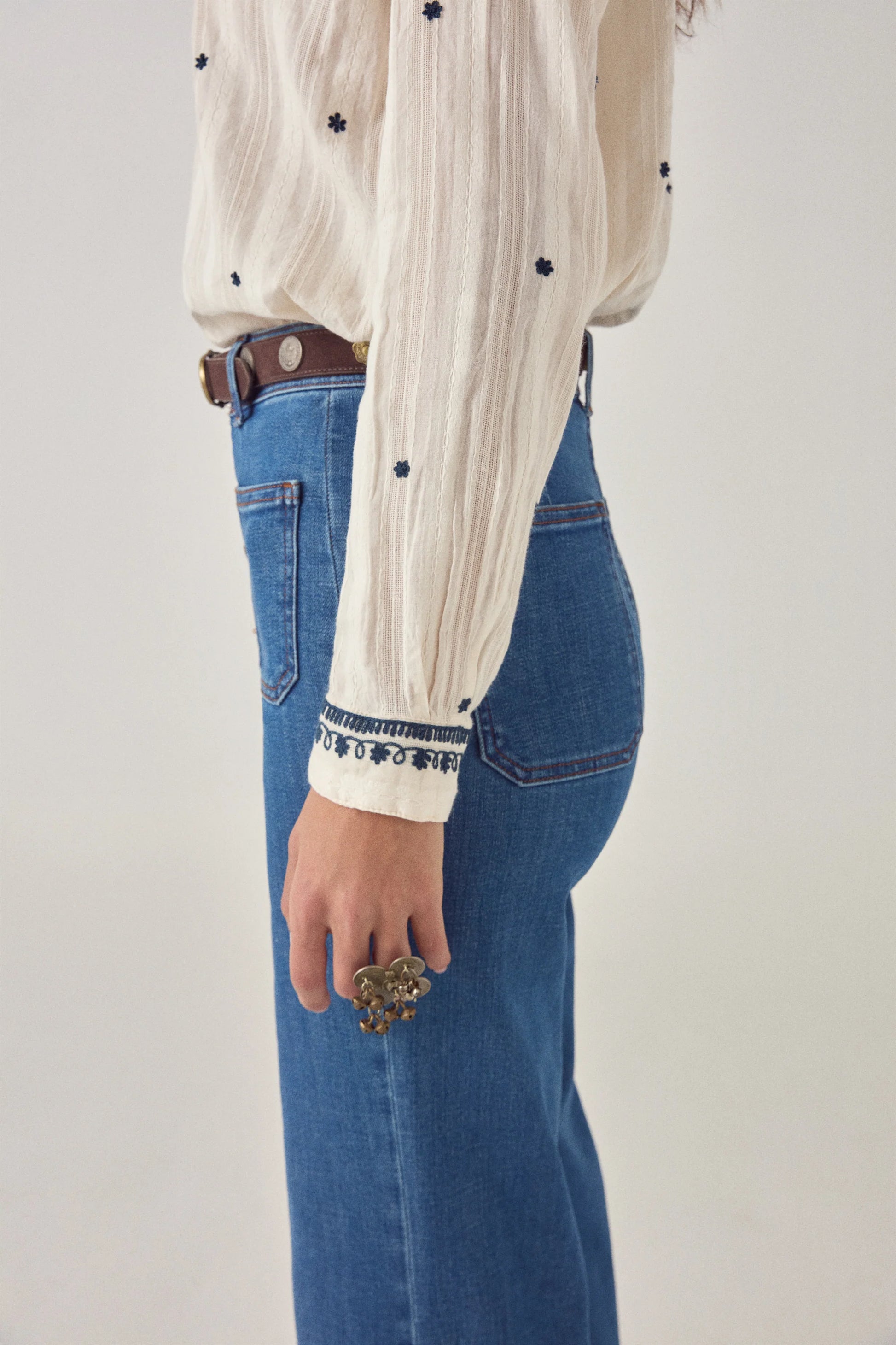 Side view of the Salinger Shirt in Cream Indigo featuring embroidered button cuffs, textured cotton dobby fabric, and scattered navy embroidered motifs.