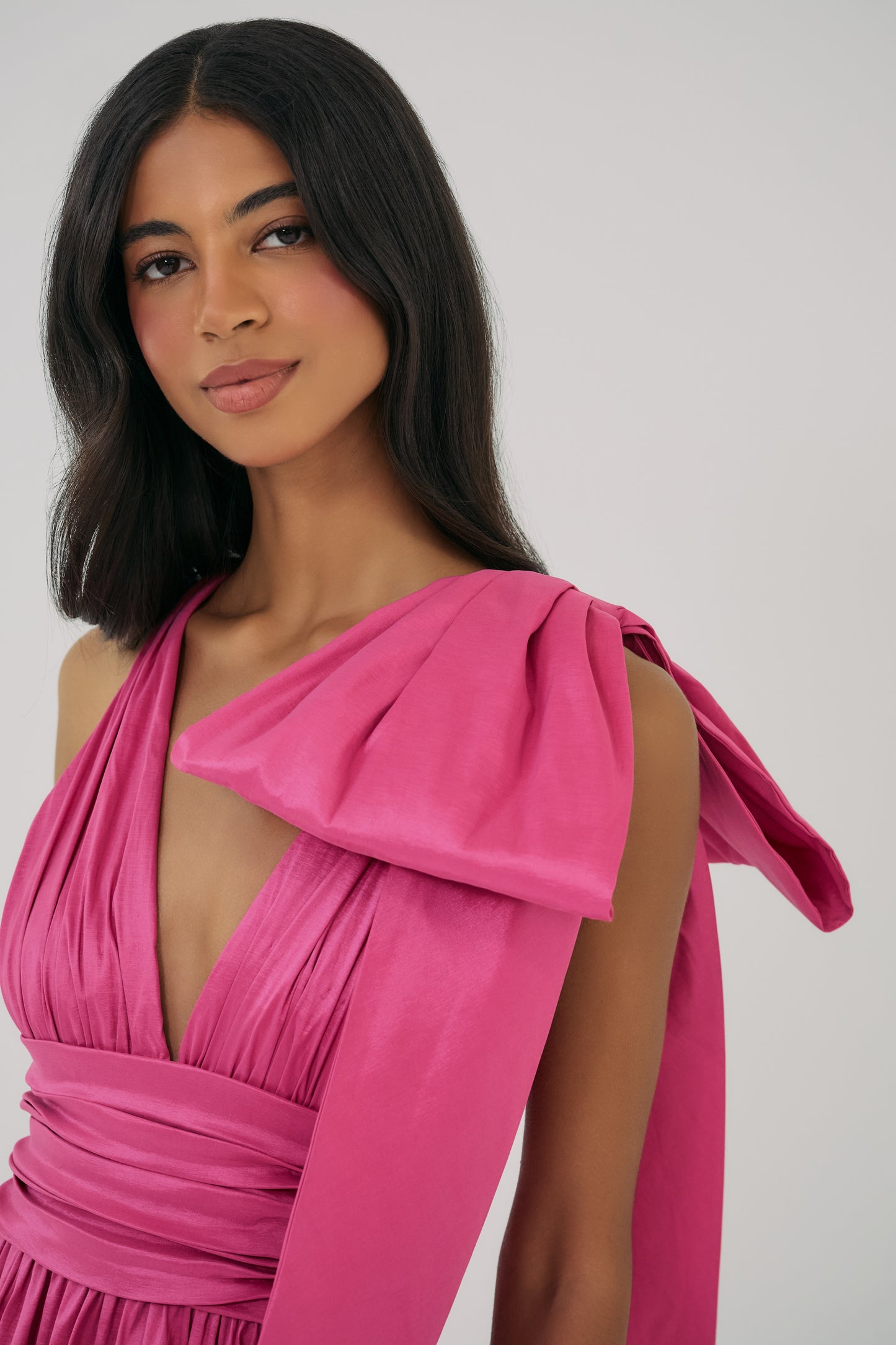 Model wearing Selba Gown in Fuchsia with draped bodice and asymmetrical shoulder tie detail