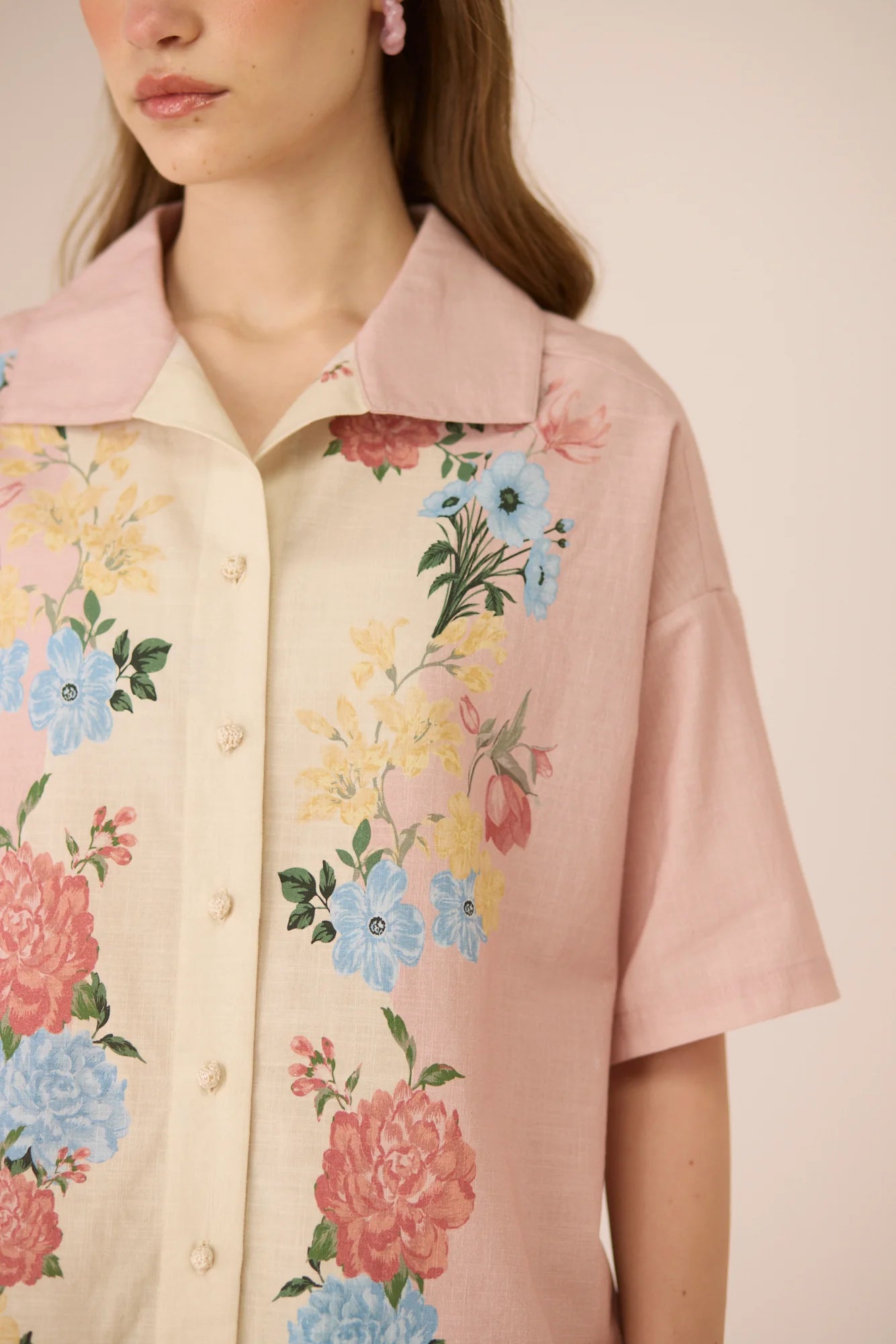 Close-up of the Shea Top showing the pastel floral placement print, crochet buttons, and soft blush collar.