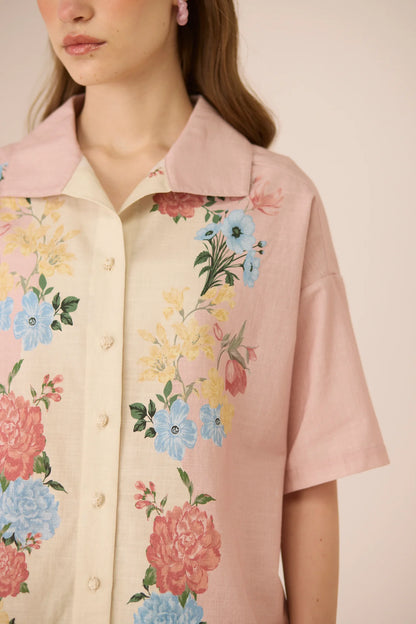 Close-up of the Shea Top showing the pastel floral placement print, crochet buttons, and soft blush collar.