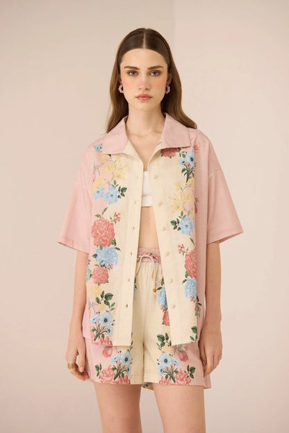 Model wearing the Shea Top in a blush and cream pastel floral placement print with relaxed short sleeves and crochet buttons.