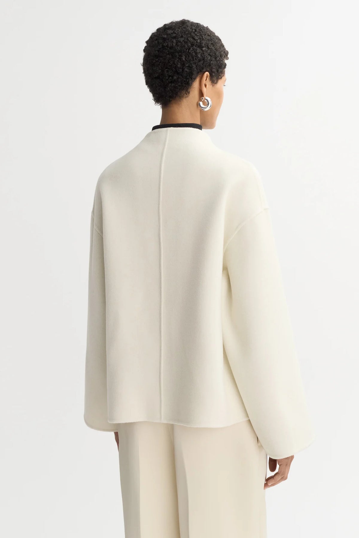 Back view of a model wearing the Short Jacket in Feather White, showing its relaxed fit and dropped shoulders.