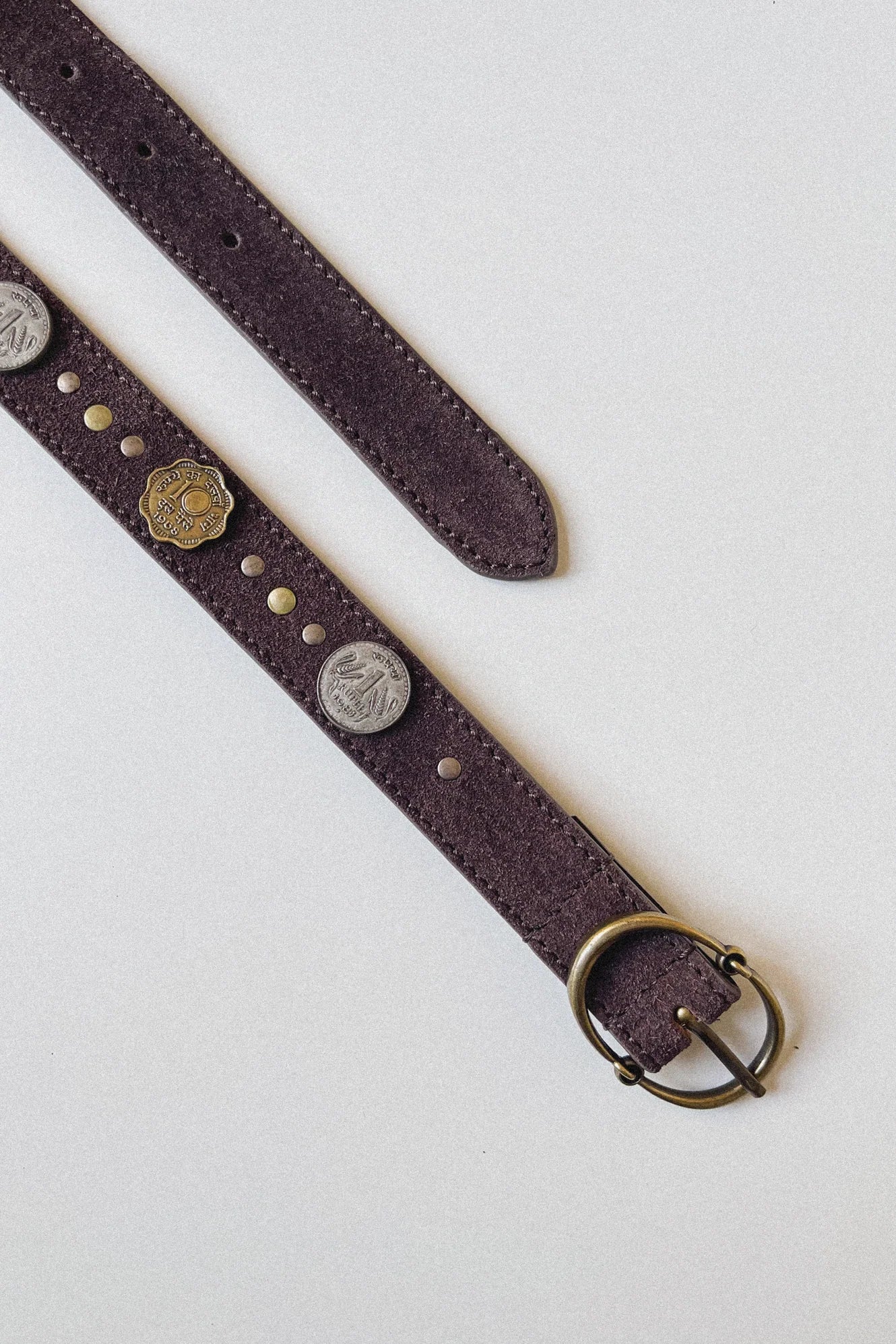Full-length view of the Sikka Belt in Tobacco featuring a brown suede leather strap, mixed metal coin accents, and an antique brass oval buckle.