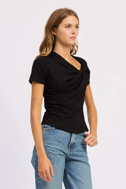 Model wearing the black Sloane Short Sleeve Shirt with an asymmetric draped neckline and relaxed fit paired with light wash denim jeans.