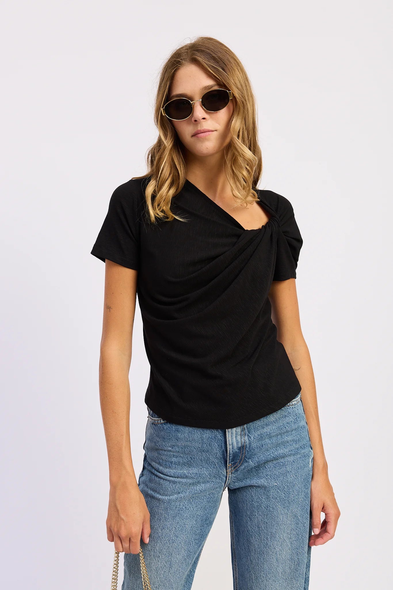 Model wearing the black Sloane Short Sleeve Shirt with an asymmetric gathered neckline and soft draped front detail.