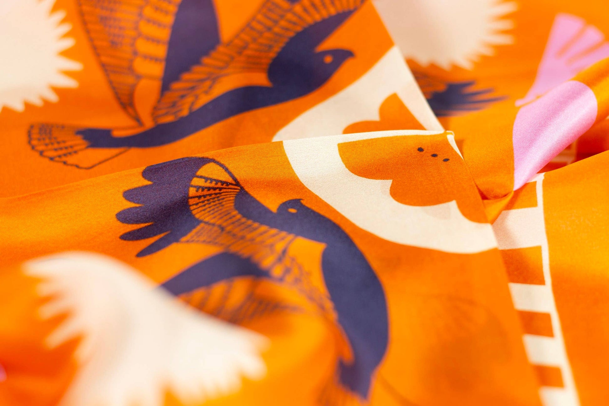 Close-up of the Soar & Sing silk scarf artwork featuring illustrated birds, floral shapes, and bright uplifting colors.