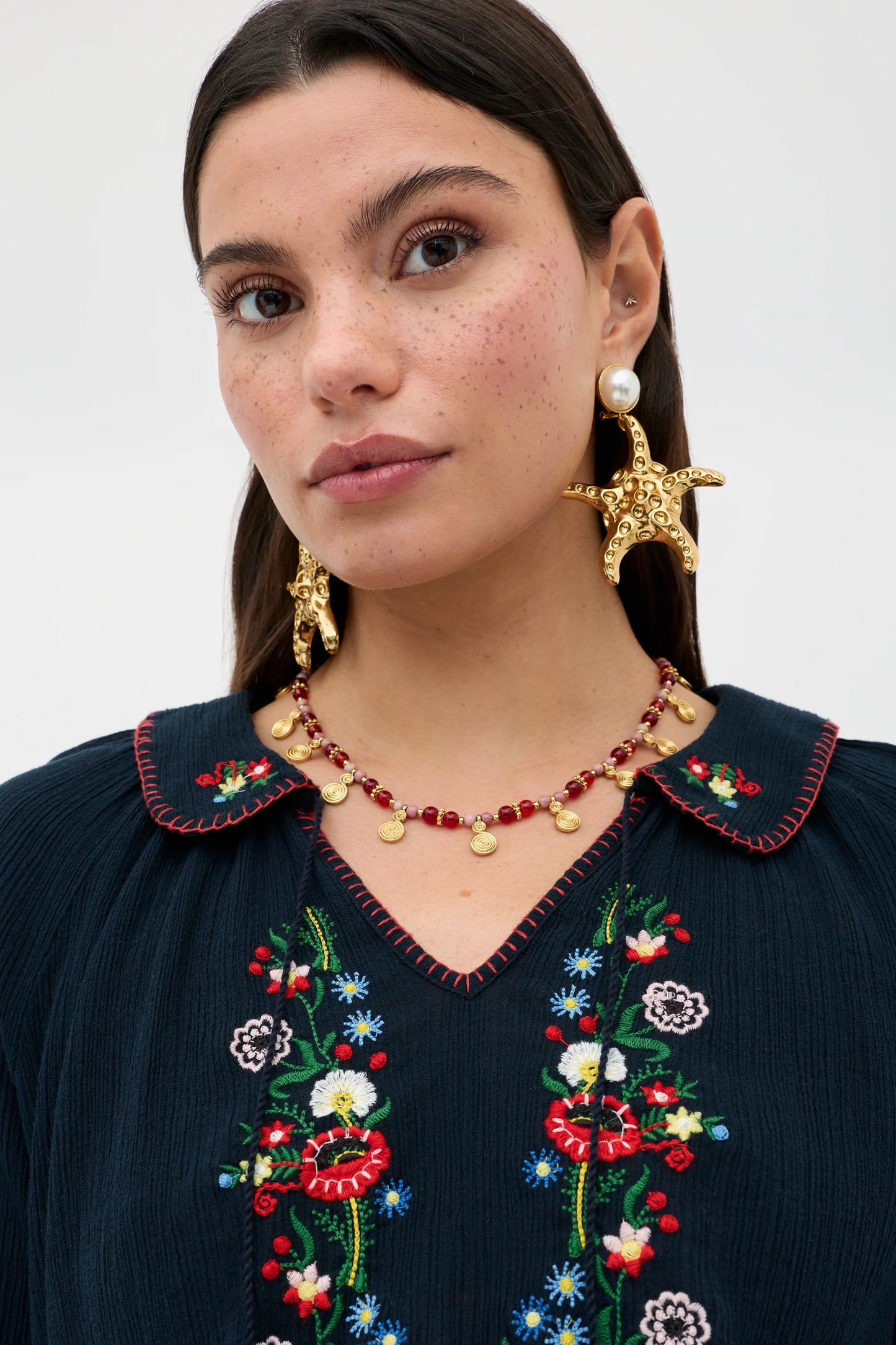 Close-up of floral embroidery and scalloped collar detail on the navy Sofira Top