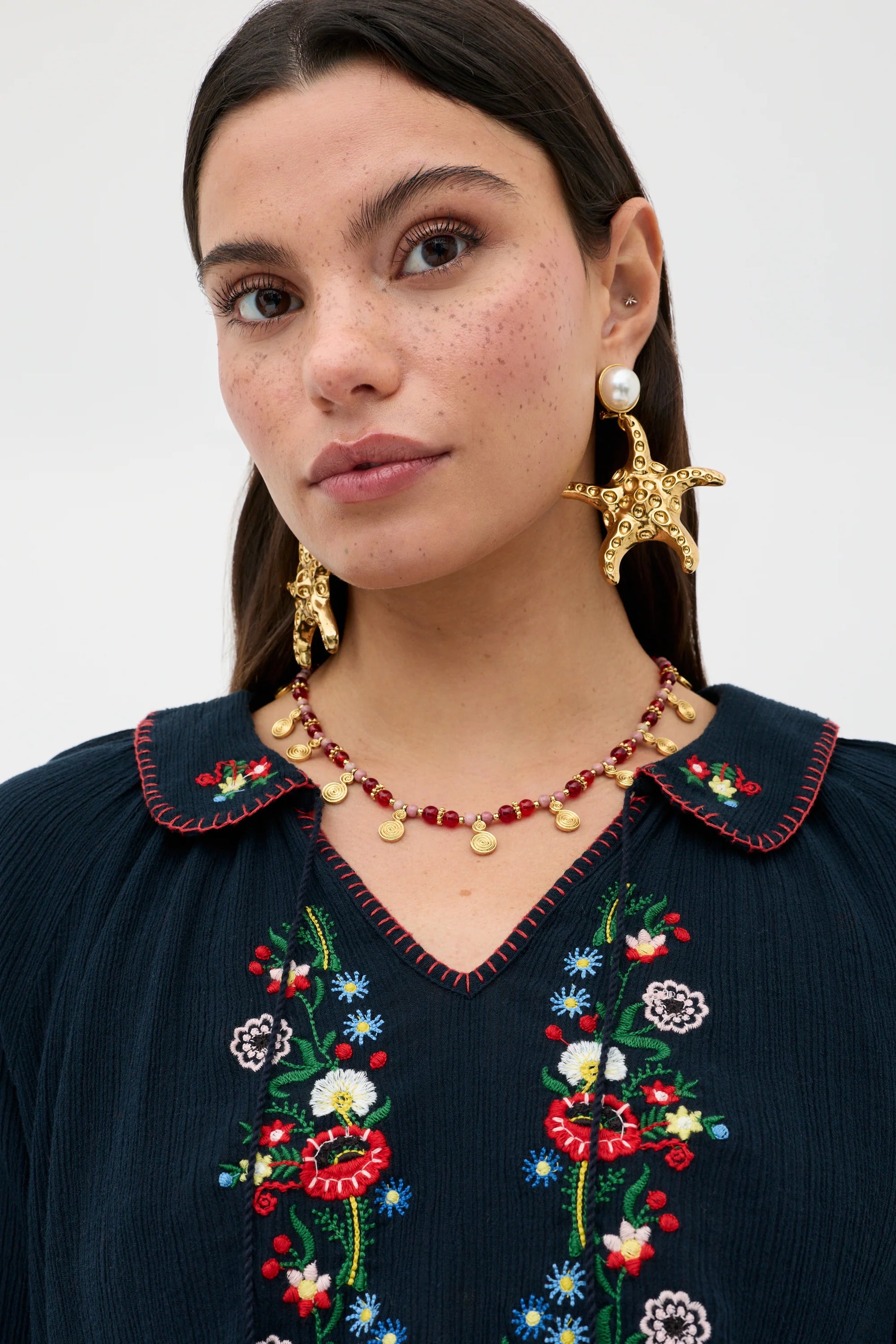 Close-up of floral embroidery and scalloped collar detail on the navy Sofira Top