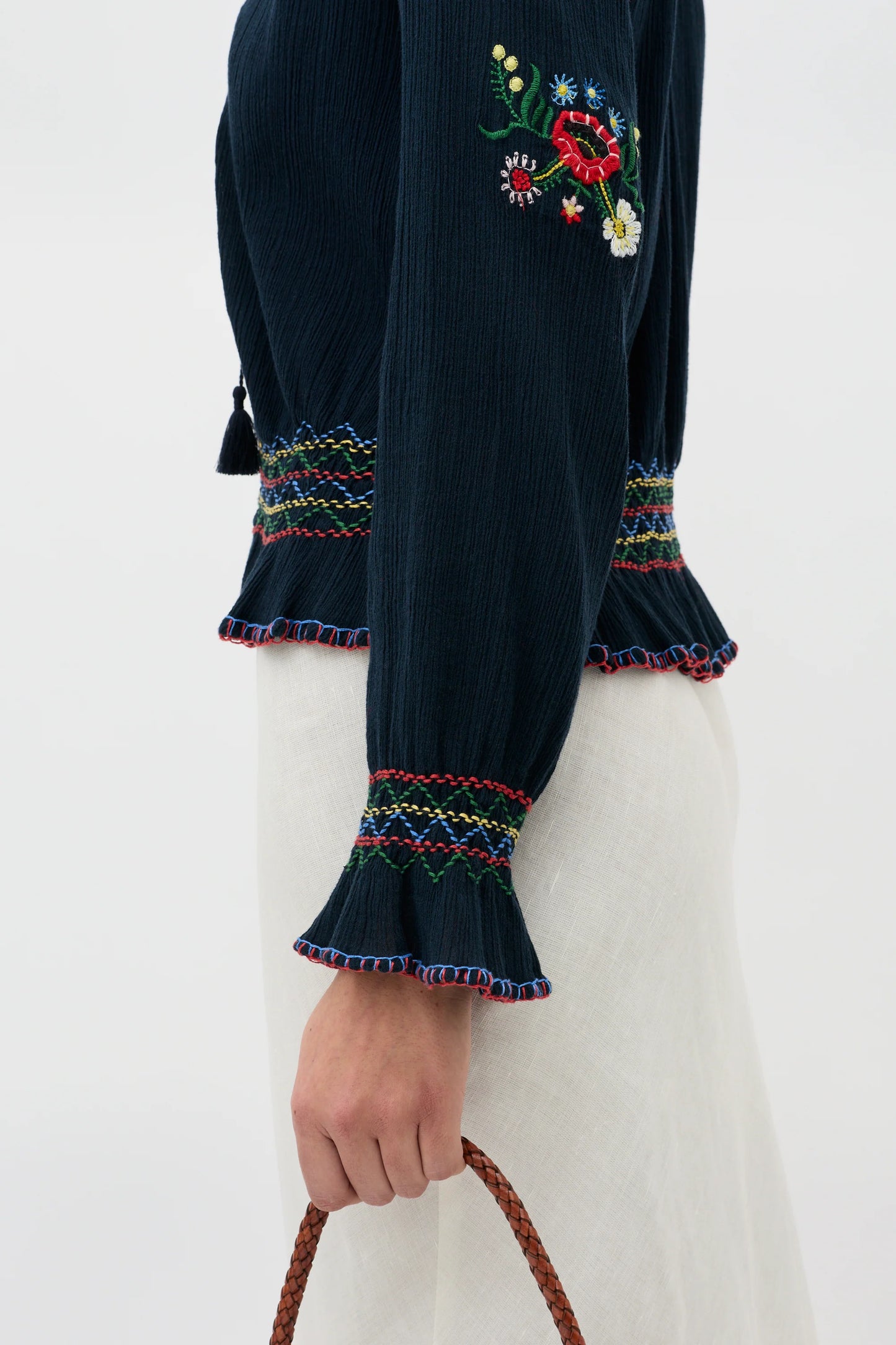 Close-up of the Sofira Top sleeve showing multicolored floral embroidery and ruffled cuff detail