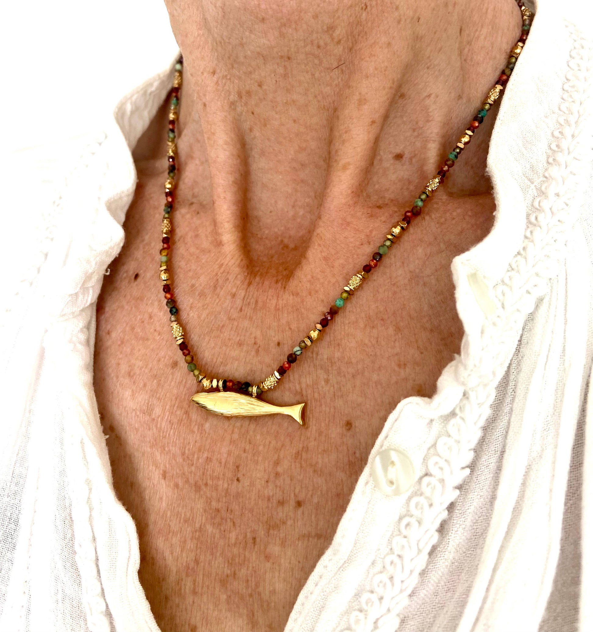 Somy Necklace worn with a white blouse, showing the multicolored gemstone strand and gold fish pendant.