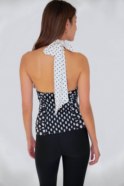 Model wearing the Sophie Contrast Mono Polka Dot Scarf Neck Top featuring a smocked back and contrast polka dot scarf neck tie in black and white satin.