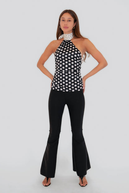 Full-length view of the Sophie Contrast Mono Polka Dot Scarf Neck Top paired with black flared pants for an elevated monochrome look.