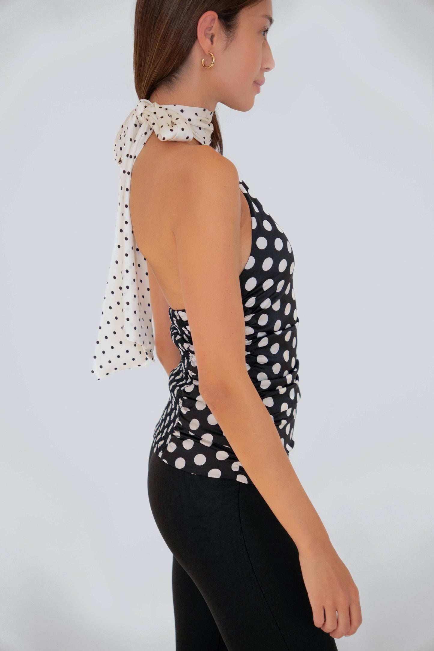 Side profile of the Sophie Contrast Mono Polka Dot Scarf Neck Top showcasing the contrast scarf neck tie and fitted ruched silhouette.