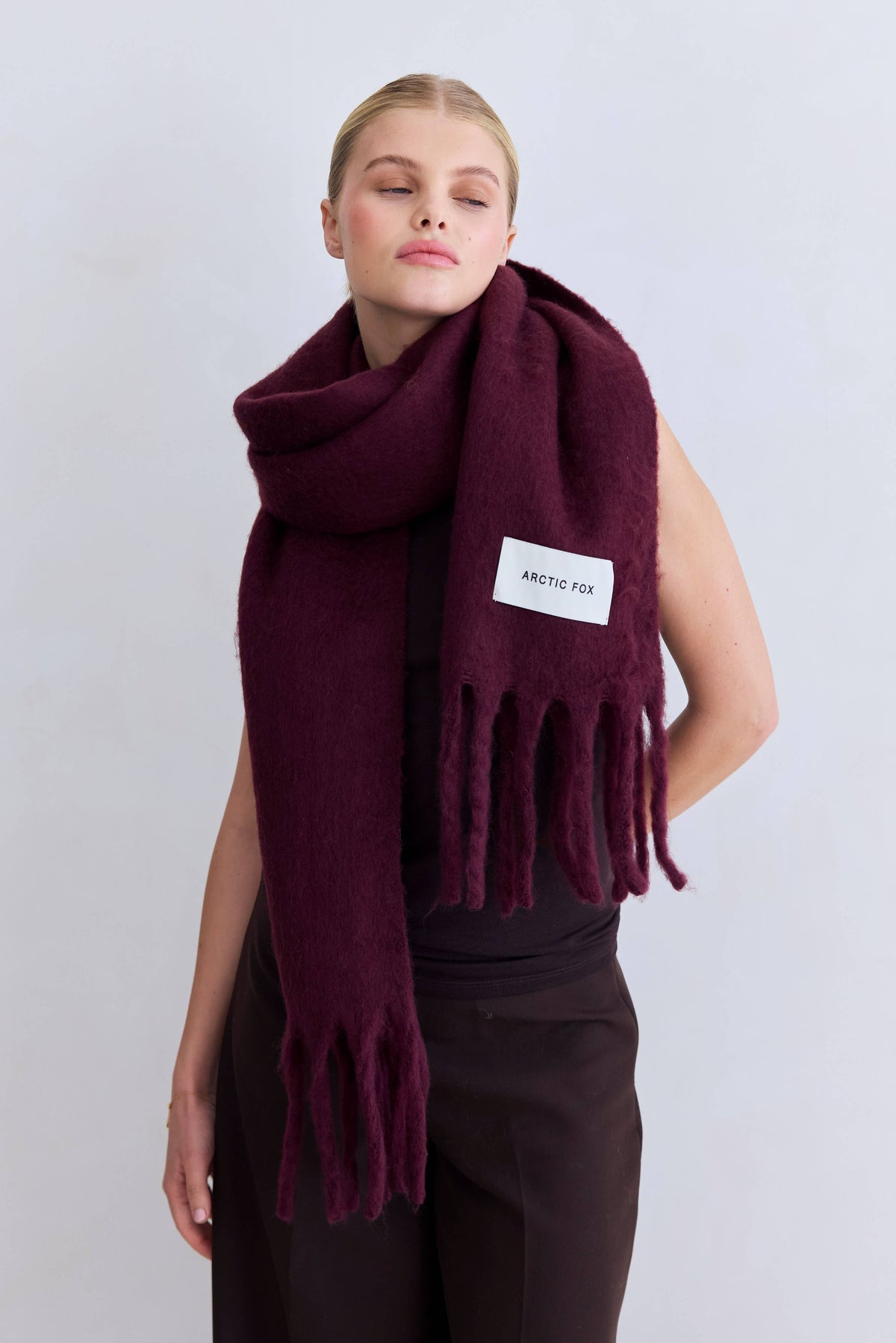 Woman wearing the Cherry Lacquer Stockholm Scarf wrapped around the neck over a black top