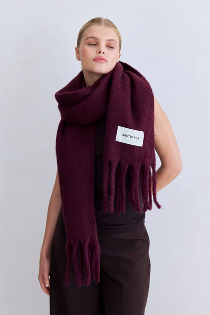 Woman wearing the Cherry Lacquer Stockholm Scarf wrapped around the neck over a black top