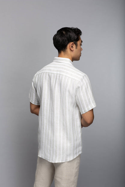 Back view of a model wearing the short-sleeve striped linen shirt with light neutral trousers.