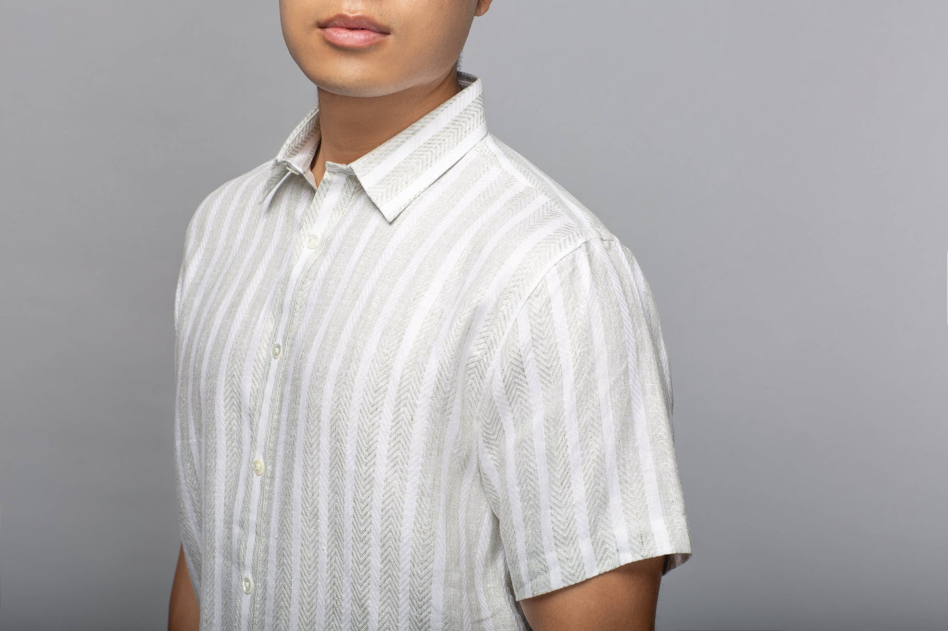 Cropped model view showing the classic collar, short sleeves, and textured vertical stripes of the linen shirt