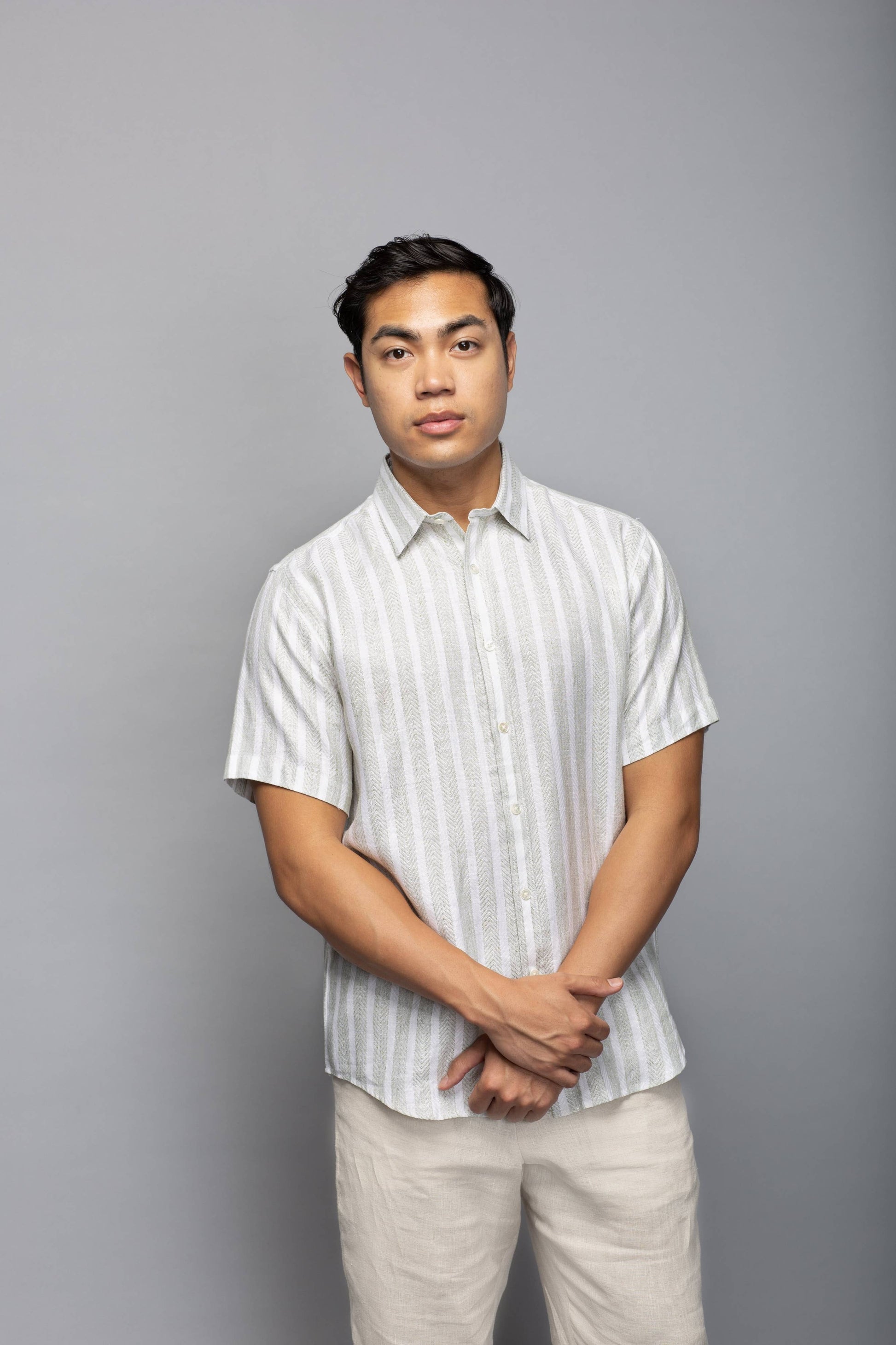 Model wearing the striped short-sleeve linen shirt with light neutral trousers, shown from the front.