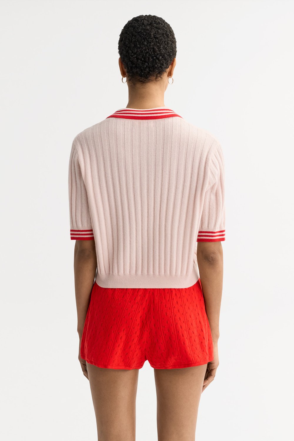 Back view of the Striped Pique cashmere polo in blush pink featuring ribbed knit texture and striped trim on the collar and sleeves.