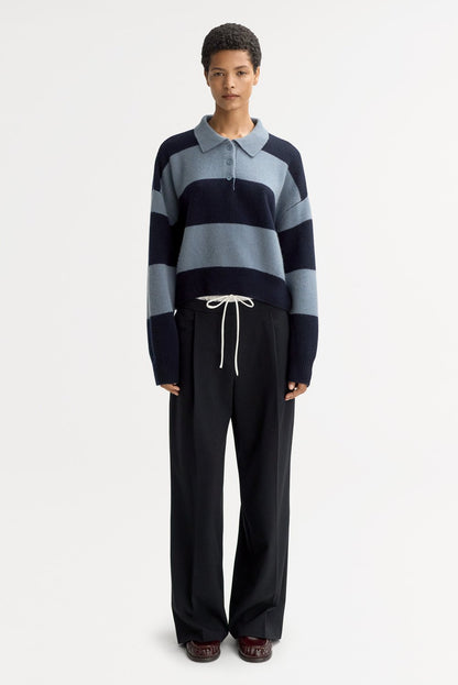 Model wearing the Striped Polo Shirt in Retro Blue with wide-leg black trousers, showcasing the cropped silhouette, polo collar, and chunky striped cashmere knit.