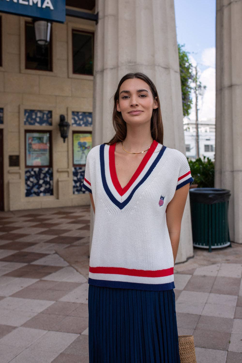 Model wearing the off-white American Shield sweater vest with red and navy V-neck trim.