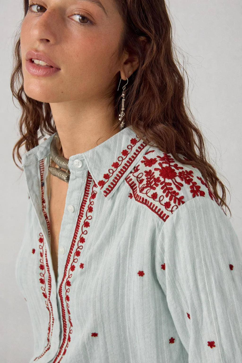 Close-up of the Texas Sun Salinger Shirt in Blue Paprika featuring burgundy floral embroidery along the collar, shoulder yoke, and button placket on a soft striped cotton fabric.